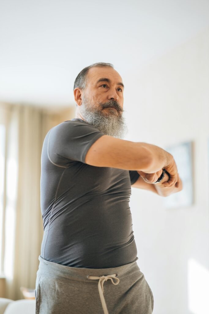 Older bearded man doing a home workout warm-up in his living room