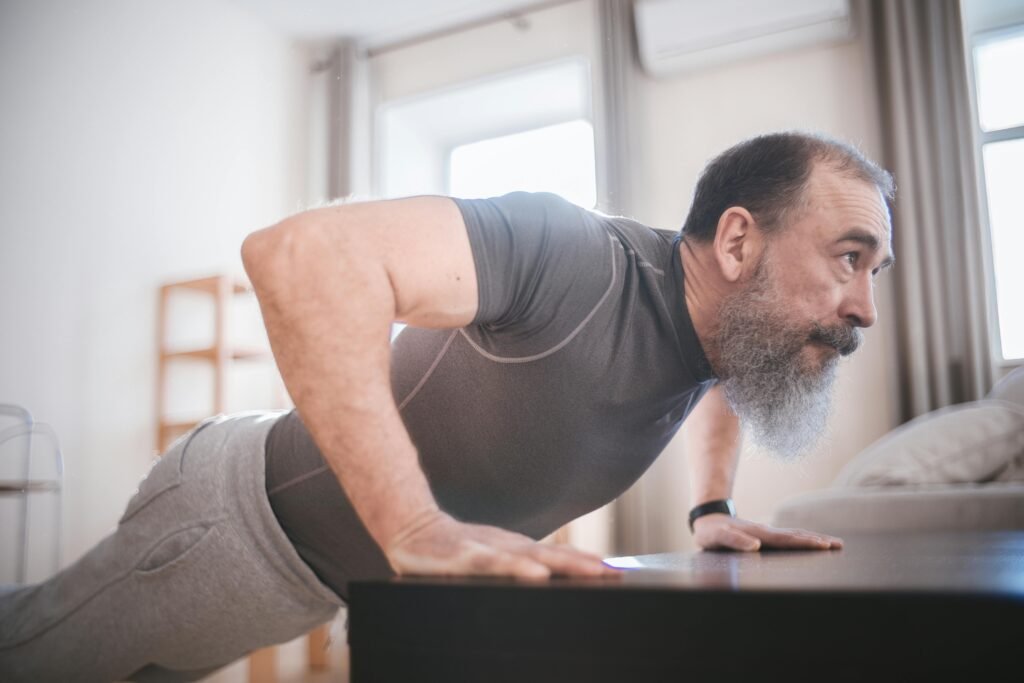 Mature man stretching arms during indoor fitness routine at home