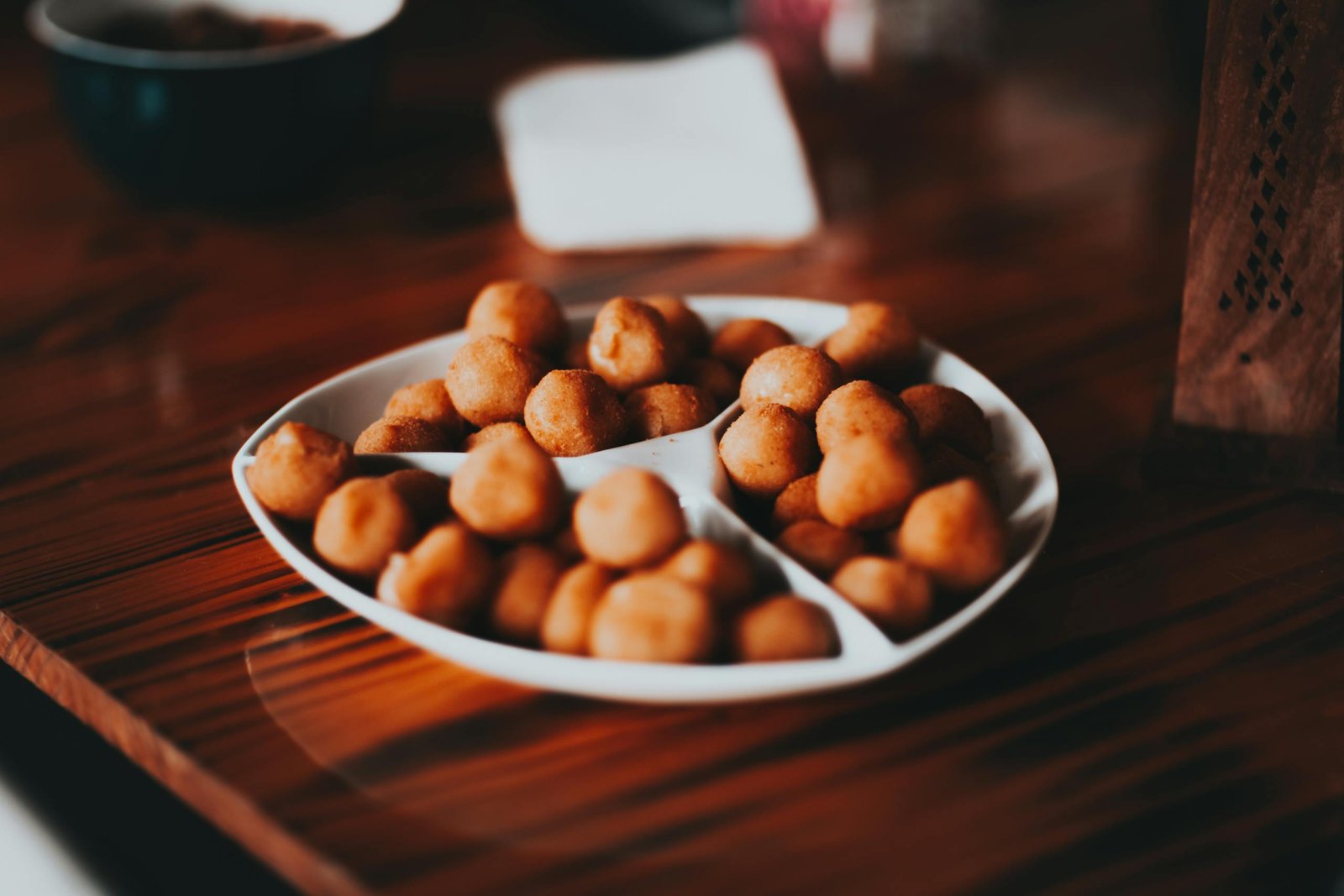 A plate of Brazilian savory snack balls served on a wooden table, indoors.