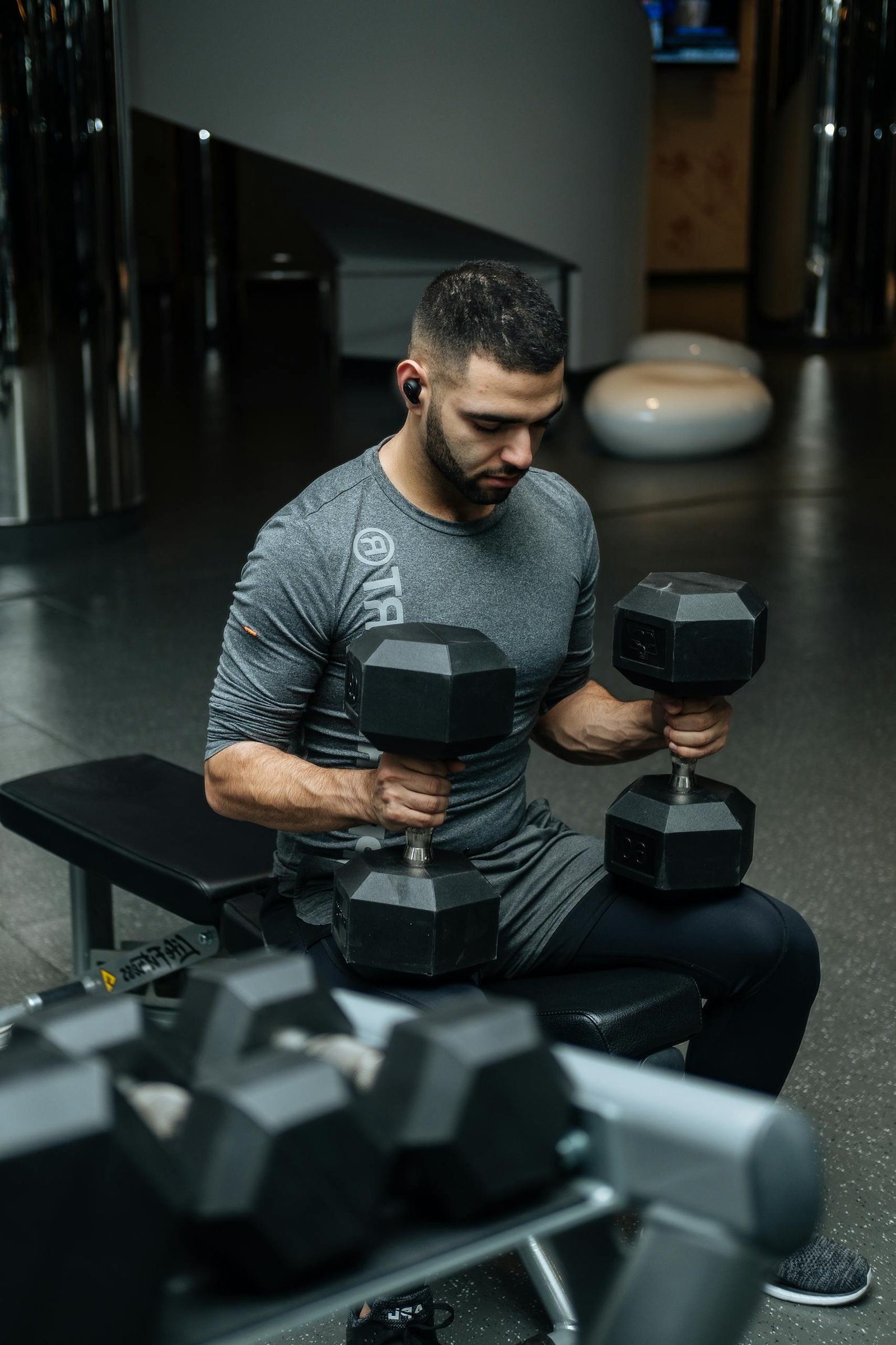 Adult man lifting dumbbells in a gym, focused on strength training workout.