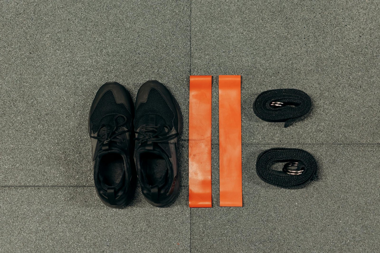 Flat lay of fitness essentials: sneakers, resistance bands, and straps for training.