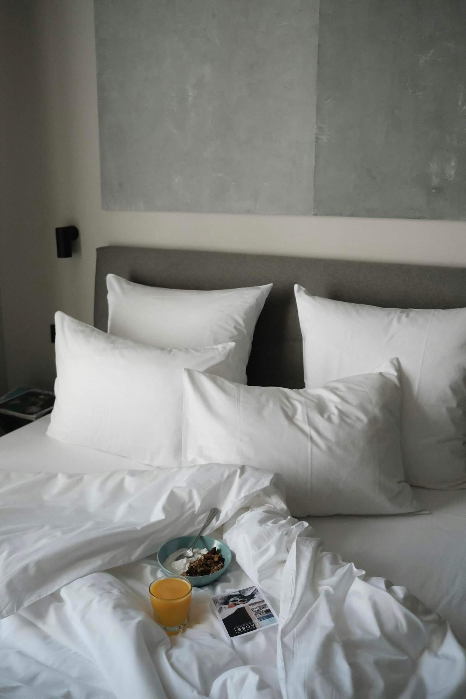 Inviting bed setup with white pillows and breakfast in a minimalist bedroom setting.